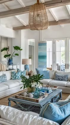 a living room filled with white couches and lots of blue pillows on top of them