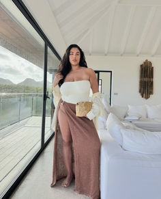 a woman standing in front of a white couch wearing a long skirt and off the shoulder top