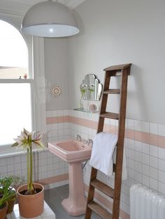 a bathroom with a ladder leaning up against the wall next to a pink sink and mirror