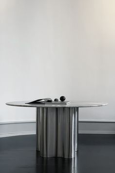 a round table with two cell phones sitting on it's side, in front of a white wall