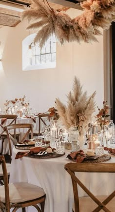 the tables are set with white linens and tall centerpieces filled with feathers