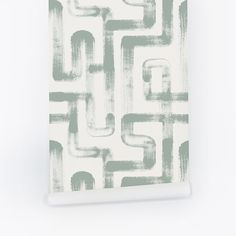 a white and grey wall hanging with an abstract design on it's side, in front of a white background