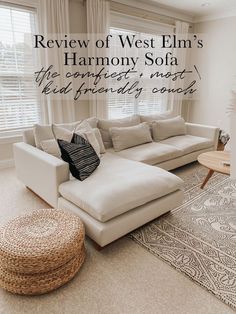 a living room with white couches and pillows on top of the rug in front of a window