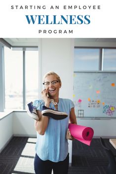 a woman talking on her cell phone while holding a pink yoga mat in an office