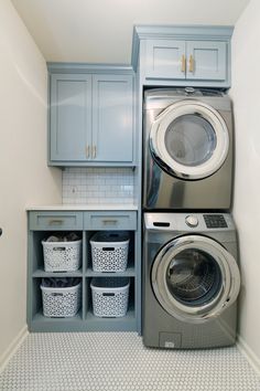 a washer and dryer in a laundry room with blue cabinets, white tile floor