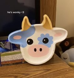 a cow shaped plate sitting on top of a wooden table next to a stuffed animal