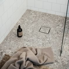 a bottle and towel on the ground in a bathroom