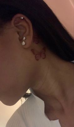 a woman with a butterfly tattoo on her left side behind the ear is looking down