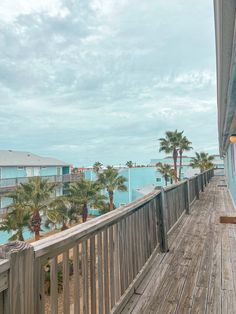 a wooden deck with palm trees on the other side and blue water in the background