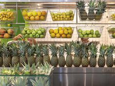 a display case filled with lots of pineapples and oranges next to other fruit