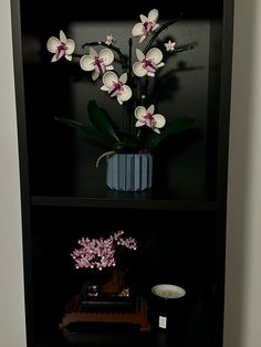 a vase with flowers on top of a black shelf