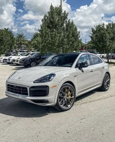 a white porsche cayen is parked in a parking lot with other cars behind it