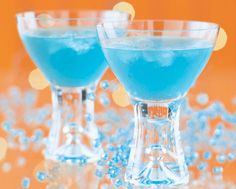 two glasses filled with blue liquid on top of a table