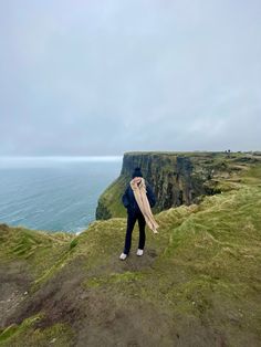 Woman at cliffs of Moher photo idea. Long neutral scarf and black beanie The Cliffs Of Moher, Cliffs Of Moher Aesthetic, Ireland Hiking Outfit, Cliffs Of Moher Outfit, Ireland Travel Aesthetic, Ireland Photo Ideas, Ireland Photoshoot