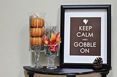 a black table topped with pumpkins next to a framed sign that says keep calm and gobble on