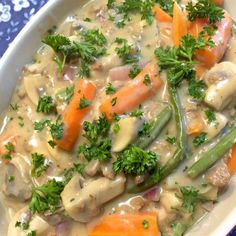 a white bowl filled with meat and veggies on top of a blue table cloth