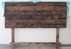 a bed frame made out of wooden planks with blue sheets on the headboard