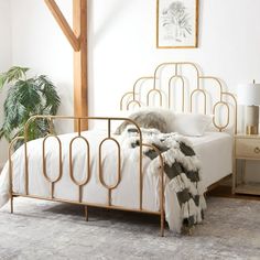 a white bed with gold metal frame and headboard is in a room that has a rug on the floor