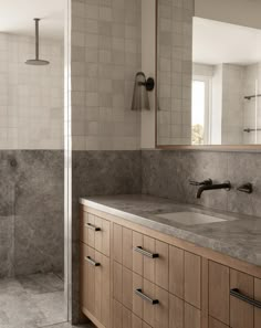 a bathroom with marble counter tops and wooden cabinetry, along with a walk in shower