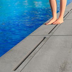 a person standing on the edge of a swimming pool with their feet in the water