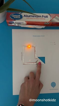 a person pointing at an electronic circuit board with a light on it's side