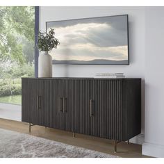 a black sideboard with two doors and a vase on it in front of a window