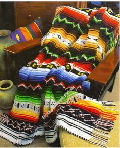 blankets and pillows are on the floor in front of a table with an old vase