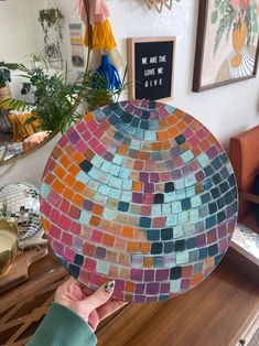 a person holding up a colorful mosaic plate