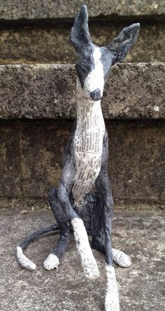 a statue of a dog sitting on top of cement steps next to a stone wall