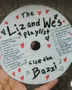 a hand holding a white disc with writing on it that says the lizard and west playlist