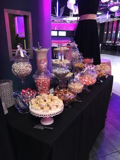 an assortment of candy and candies on a table in a room with purple lighting