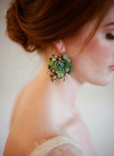 a woman with red hair wearing green earrings