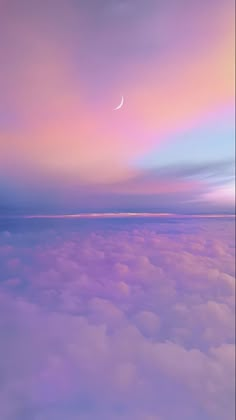 an airplane wing flying above the clouds at dusk with a half moon in the sky