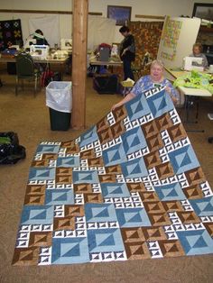 a woman is holding up a quilt in an art studio