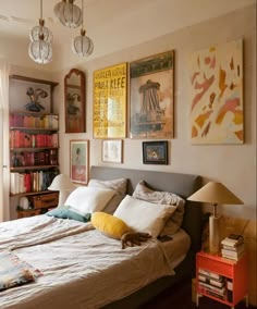 a bed sitting in a bedroom next to a window with lots of pictures on the wall