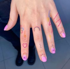 a woman's hand with pink and yellow nail polish on her fingers, holding onto the