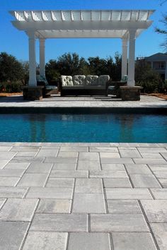 an outdoor patio with a couch next to a pool and pergolated seating area