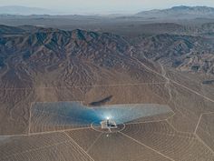 an aerial view of the desert with mountains in the background and solar panels on the ground