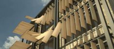 an architectural structure with wooden slats on the outside and sky in the background,