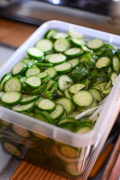 a plastic container filled with sliced cucumbers on top of a wooden countertop