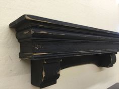 an old black shelf is hanging on the wall