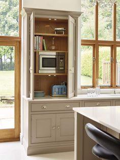 a kitchen with an oven, microwave and table in front of large open windows that look out onto the yard