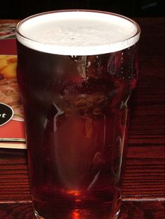 a tall glass filled with liquid sitting on top of a table next to a book