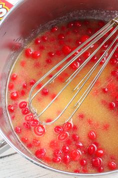 a metal bowl filled with red berries and whisk