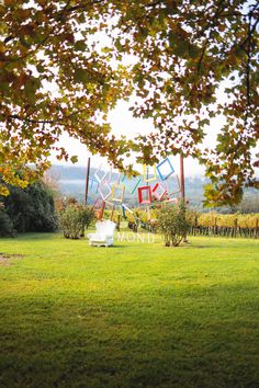 a chair sitting on top of a lush green field next to a tall metal sculpture