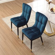 two blue chairs sitting on top of a wooden floor next to a white coffee table