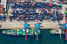 an aerial view of shipping containers and cargo ships in the water near a dock area