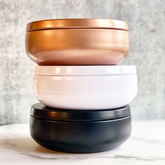 three bowls stacked on top of each other in different colors and sizes, sitting on a marble surface