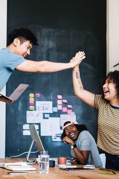 two young men are giving each other high fives in front of a blackboard