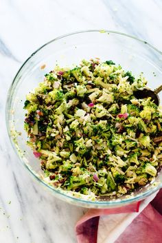 a glass bowl filled with broccoli and other vegetables on top of a table